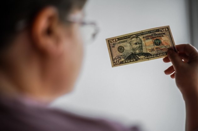 Женщина смотрит на долларовую банкноту