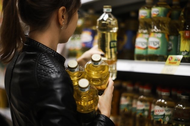 Женщина покупает растительное масло в магазине