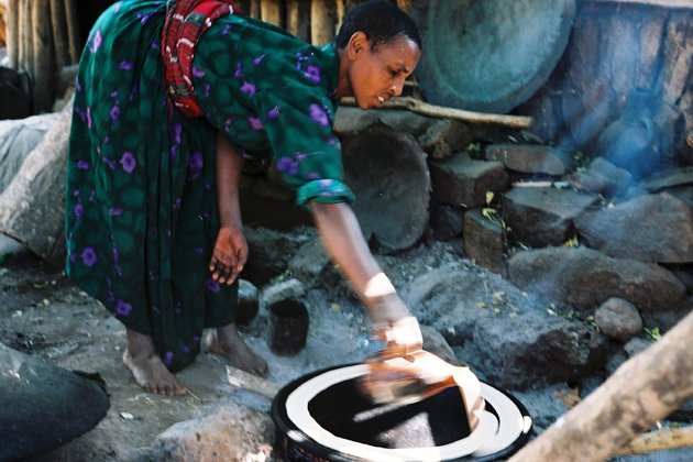 Женщина готовит пищу на огне